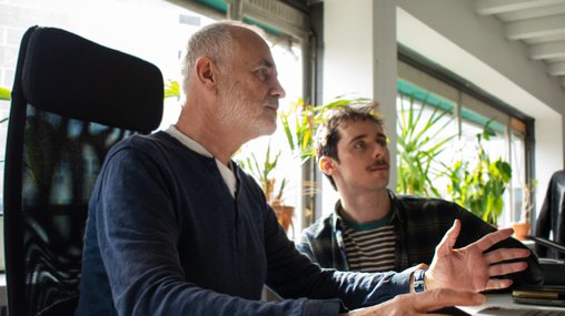 Rob and Tom discussing work at a laptop - Office - Day